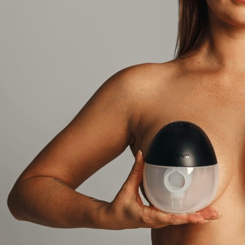 Holding wearable black and clear breast pump to chest