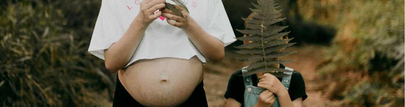 Pregnant person and child holding ferns